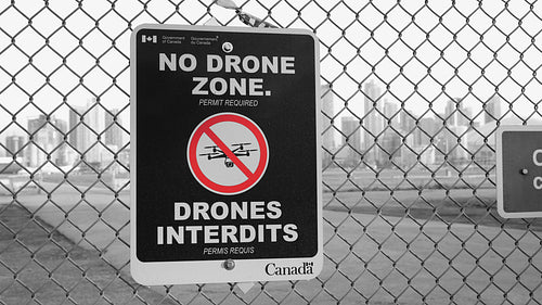 No Drone Zone sign at fence outside Toronto Island Airport. Black & white & red. 4K stock video.