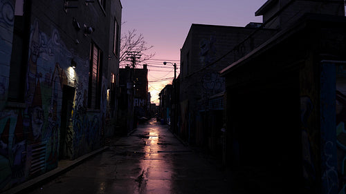 Dark industrial graffiti alley. Wet pavement and purple sunset sky. Toronto. 4K.