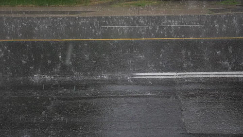 Slow motion shot of heavy rain with hail falling on road surface. HD.