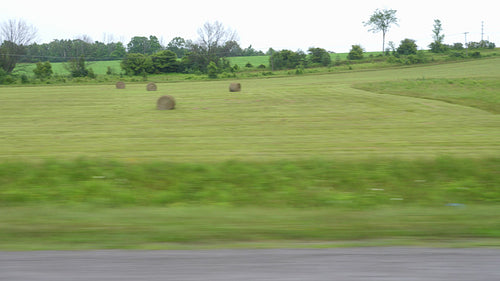 Rural drive past farmers field with hay bales. Ontario, Canada. 4K.