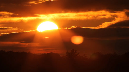 Dramatic orange sunset with sun moving behind clouds. Time lapse. HD.