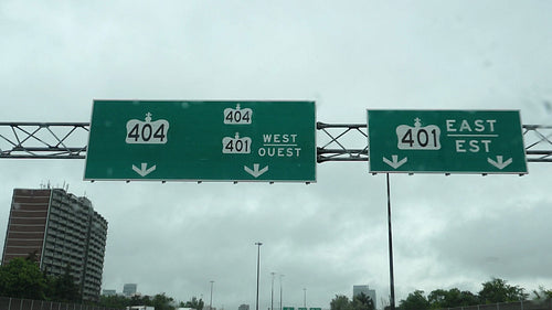Slow motion shot in rain passing sign for Highways 404 and 401. Toronto. HD.