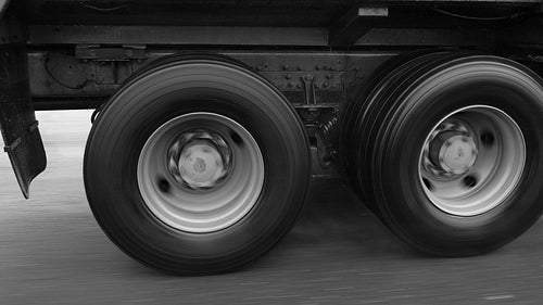 Slow motion shot. Truck wheels spinning on commercial truck in the rain. Black & white. HD.