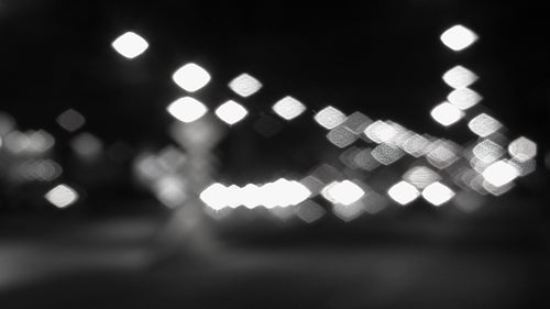 Pretty city lights. Defocused lights at downtown intersection. Black & white. HD video.