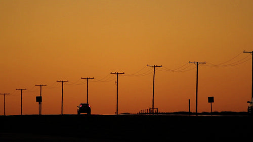 Dusk traffic with orange sky and telephone poles. Saskatchewan, Canada. HD.