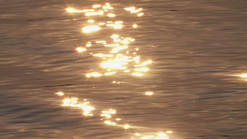 Sparkling slow motion sunset water. Golden pink reflections on the surface. HD.