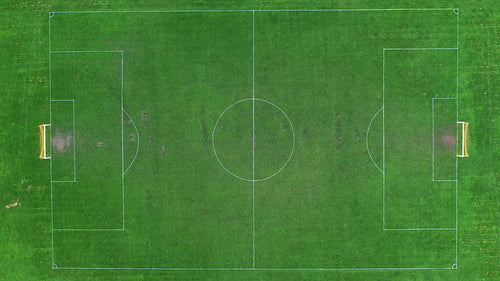 Aerial drone shot rising above football soccer field revealing whole pitch. Time lapse. 4K.
